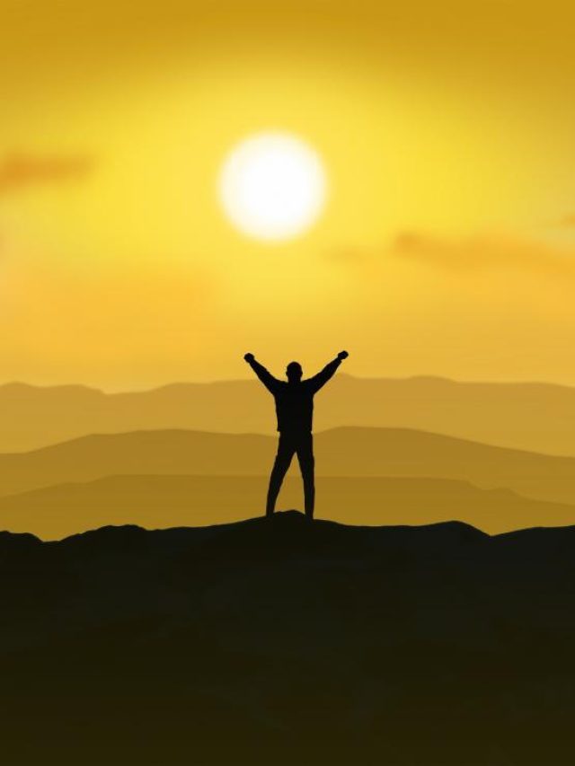 victorious-man-standing-on-the-top-of-a-mountain-raising-